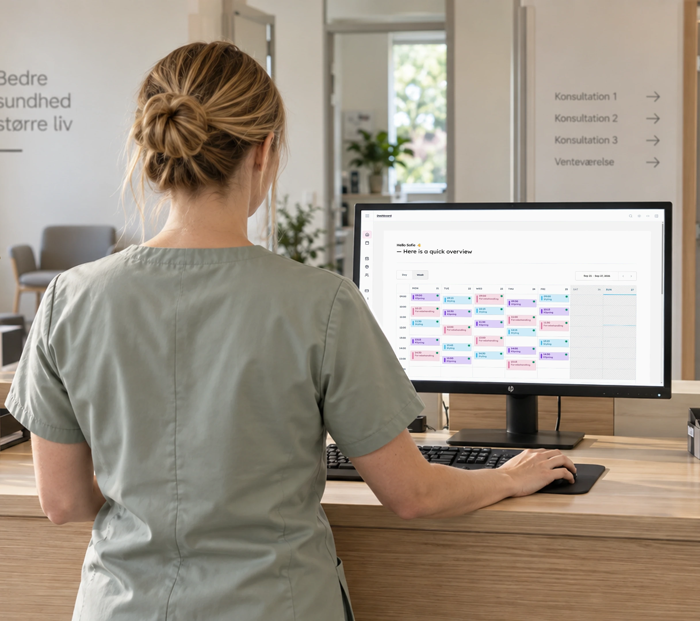 Klinikmedarbejder set bagfra ved en computer med Daily-systemets kalender.