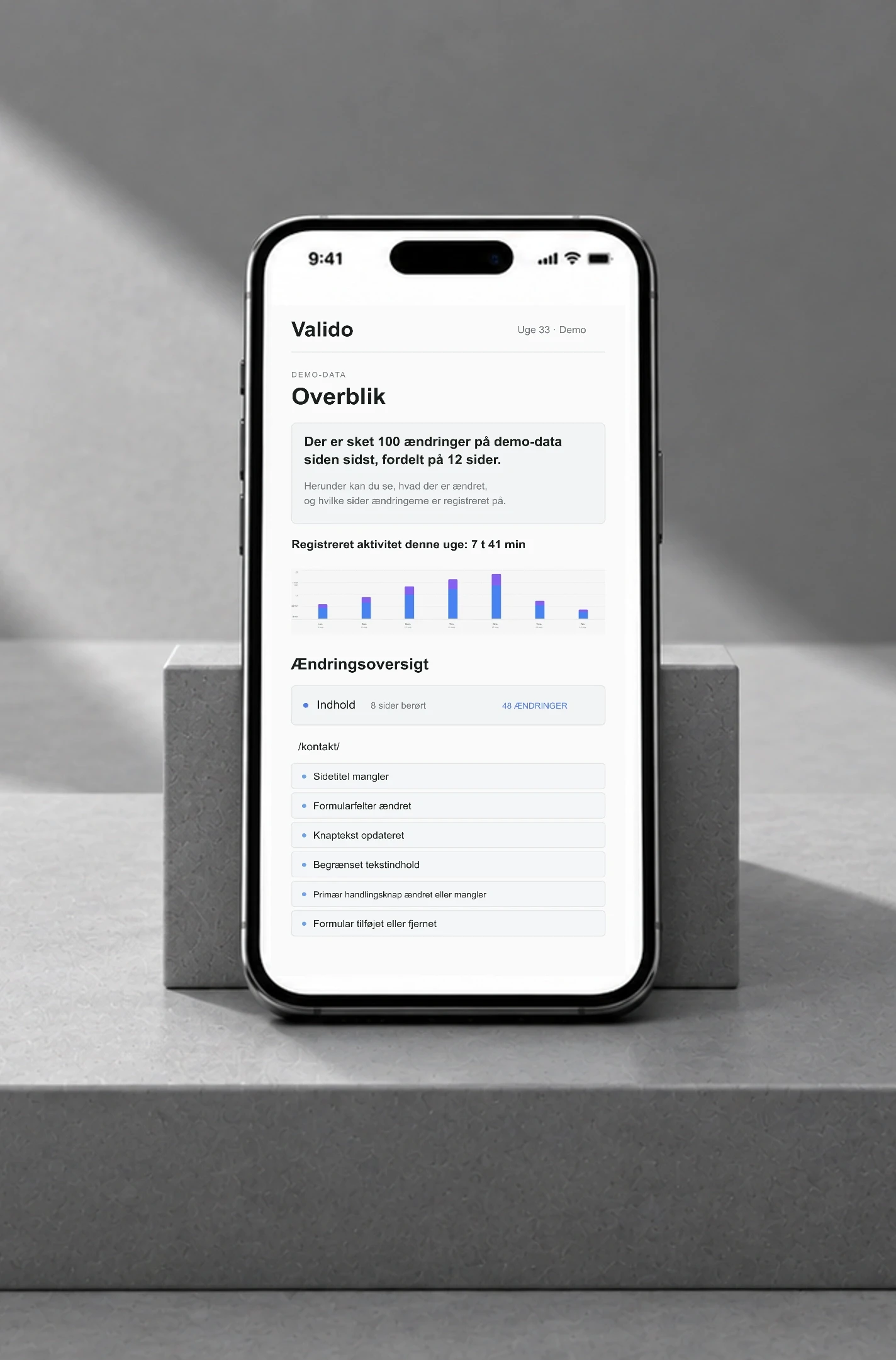 Valido demo-SEO-rapport på telefon, vist tæt på på en grå skulpturel baggrund.