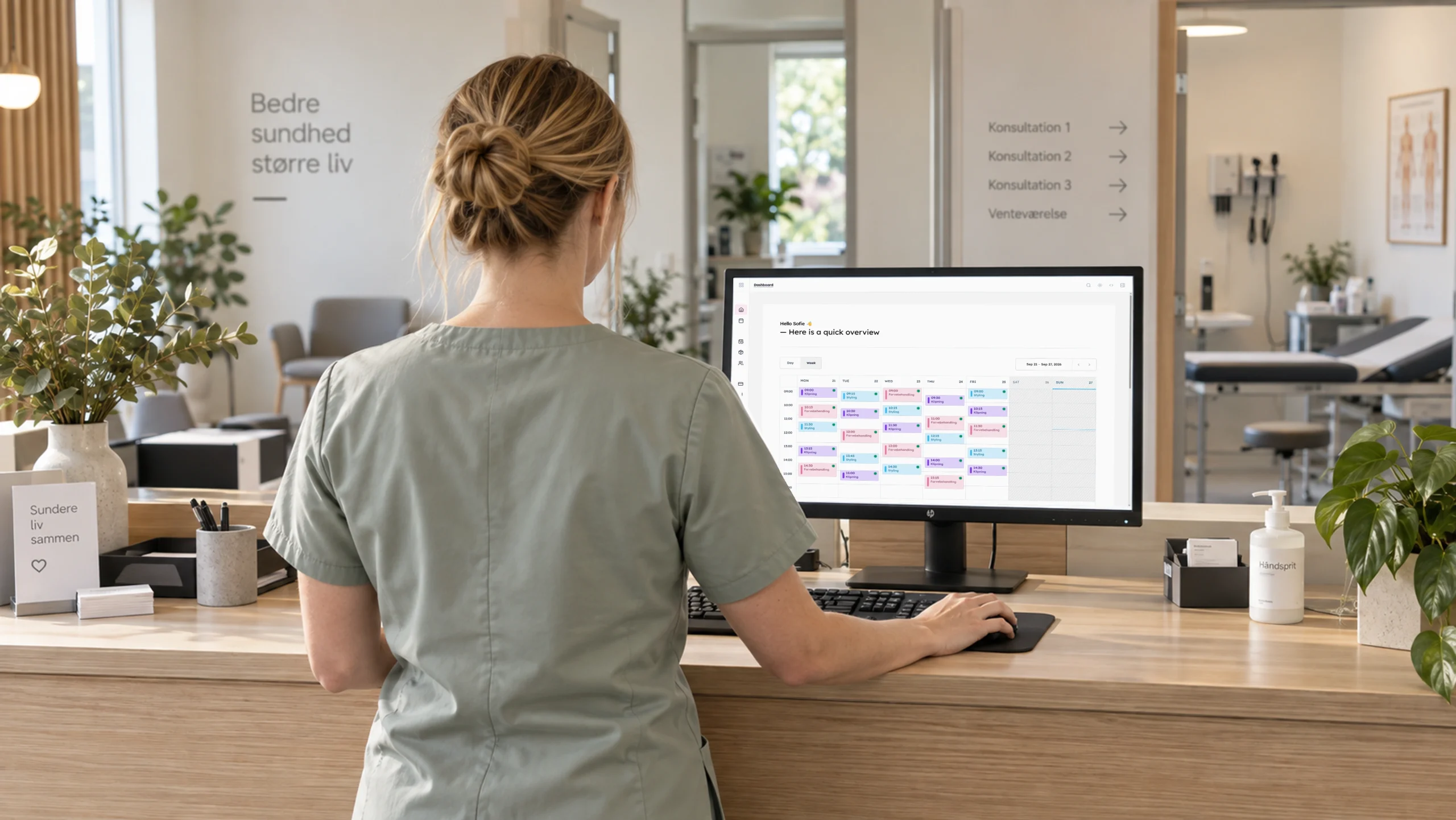 Daily: en klinikmedarbejder set bagfra bruger bookingsystemet på en computer ved klinikkens reception. Ingen ansigter er synlige.